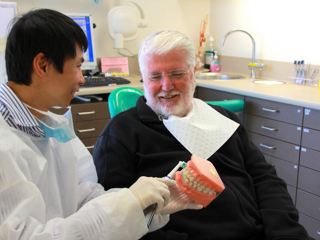 Dr Steven Du showing a patient about tooth brushing techniques